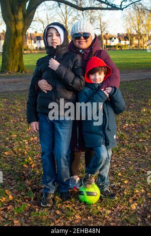 Portrait of a mother and her two sons in the local park on a winter's day. Stock Photo