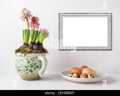 Blossom pink hyacinth in flower pot and plate of chicken and quail eggs. The first spring flower. Easter decoration. Copy space in frame. Stock Photo