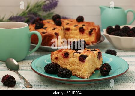 Piece homemade pie with blackberries and coconut chips on a light blue background. Closeup Stock Photo