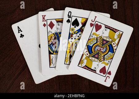 Ace of clubs, king of diamonds, queen of spades, and jack of hearts playing cards on wood table Stock Photo