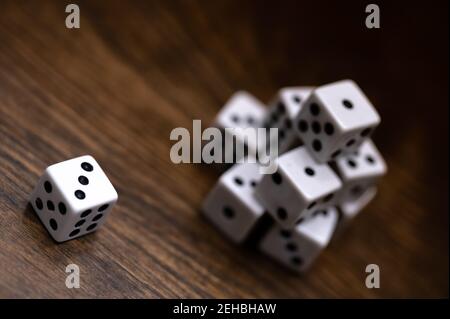 Top view of dice on wood table showing a three with a stack of dice in the background Stock Photo