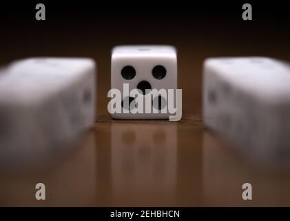 Front view of dice showing a five with two rows of dice leading to it on wood table with reflection Stock Photo