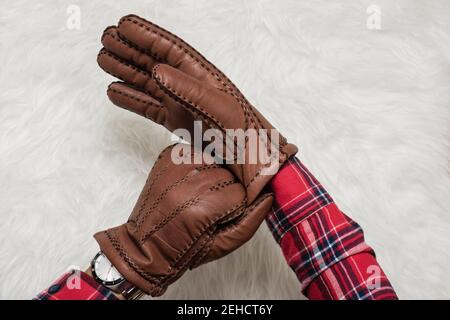 closeup men's hand wearing the brown leather gloves over white fur. Stock Photo