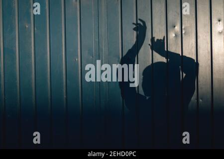 Relaxed young stylish ethnic female in casual clothes standing on street near aged wall raised arms in sunlight Stock Photo