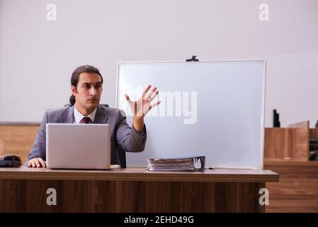 Young handsome business trainer in the office during pandemic Stock Photo