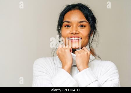 Long-haired brunette Asian Woman dressed in a white sweater looking at camera Stock Photo