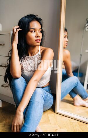 Long-haired brunette Asian Woman looking in the mirror Stock Photo
