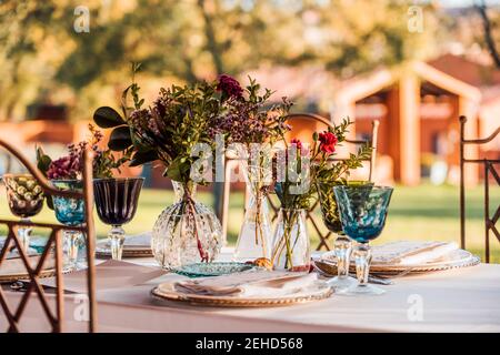 Close-up of served festive table with crystal glasses cutlery napkin on plate near bunch of fresh flowers for wedding and menu card Stock Photo