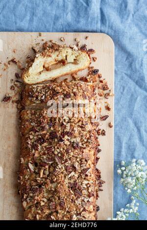 Top view of tasty apple pastry with crunchy nut pieces on cutting board on crumpled fabric Stock Photo