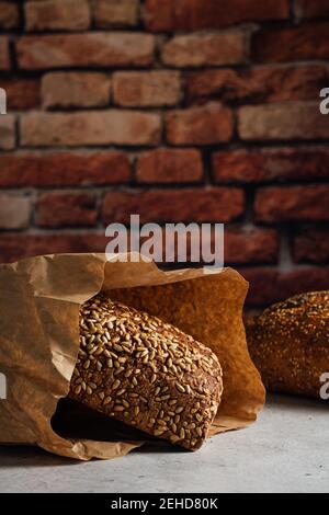 Tasty whole bread with brown crust and sunflower seeds on top on table in daylight Stock Photo