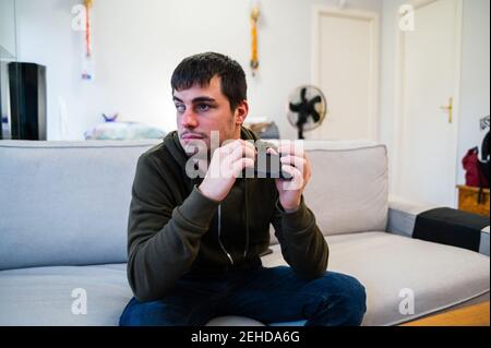 Male with eyesight disability scrolling mobile phone while sitting on couch at home Stock Photo