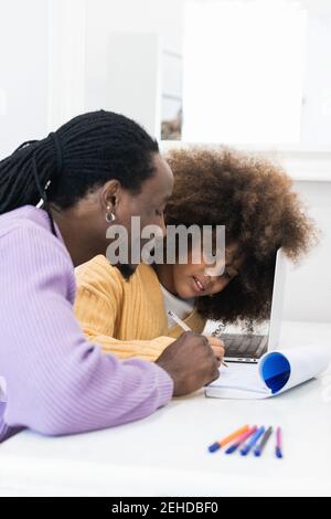 African American dad sitting at table with girl surfing netbook while preparing task for school Stock Photo