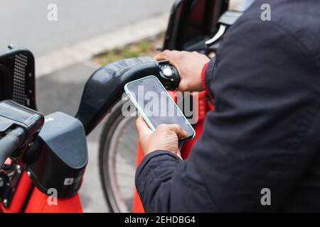 From above cropped unrecognizable masculine black male watching cellphone while using bike parking application in town Stock Photo