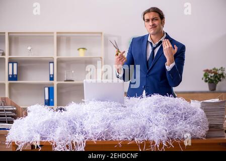 Young male employee cutting papers in the office Stock Photo