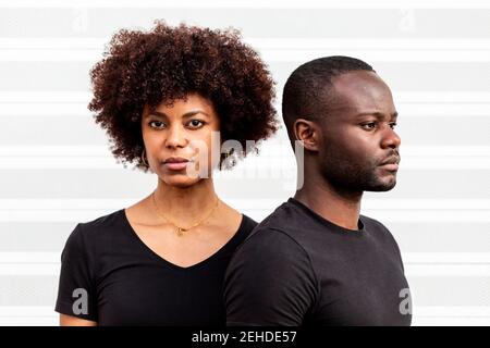 Young ethnic Woman with Afro hairstyle near bearded male partner in casual outfit on light background Stock Photo