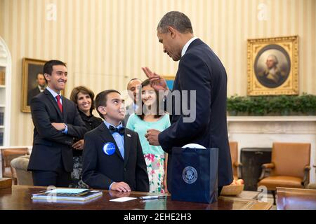 President Barack Obama visits with Sullimon Azai, a 10 year-old Make-A-Wish recipient, and his family in the Oval Office, June 17, 2014. Stock Photo