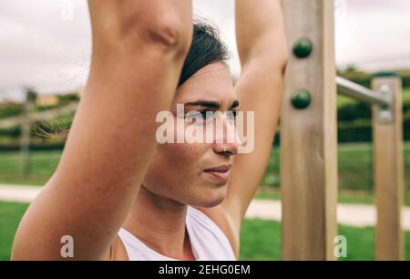 Closeup of female athlete hanging from a bar in a park Stock Photo
