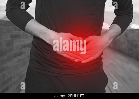 Man in black sports clothes with stomach side stitch or cramps during running.  Stock Photo