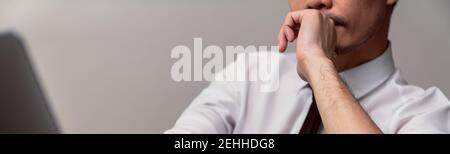 Serious businessman in suit hands touching on the chin and looking on the computer laptop at office. Stock Photo