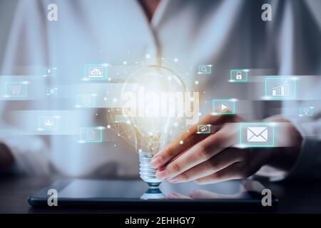 Woman hand holding light bulb with innovative and creativity are keys to success and show technology icon social media. Stock Photo