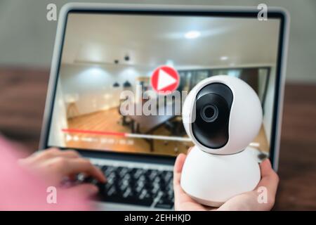 Hand holding CCTV camera and using laptop with looking video record, surveillance technology. Stock Photo