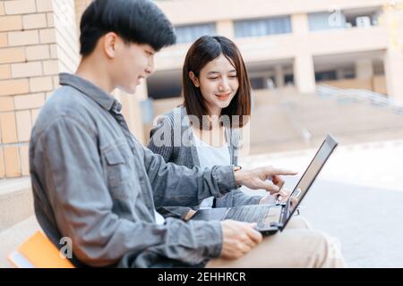 teenager sitting on stair at college campus with school books and a laptop computer doing homework. Education concept. Stock Photo
