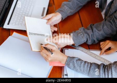 High school or college students  group catching up workbook and learning tutoring on desk and reading, doing homework, lesson practice preparing exam. Stock Photo