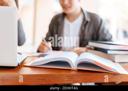 High school or college students  group catching up workbook and learning tutoring on desk and reading, doing homework, lesson practice preparing exam. Stock Photo