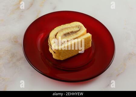 Slice of tiramisu coffee cream cake roll on red glass plate on table Stock Photo