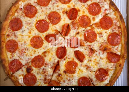 Top view flat lay of one whole sliced pepperoni pizza in the box. Stock Photo