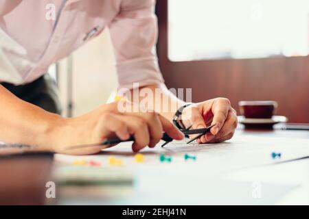 Engineering hands hold vernier caliper working and checking drawing blue print scale on workplace. Stock Photo