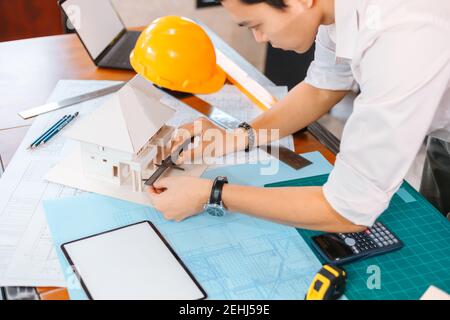 Engineering hands hold vernier caliper working and checking house model scale between meeting with businessman and businesswoman. Stock Photo