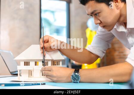 Engineering hands hold vernier caliper working and checking house model scale between meeting with businessman and businesswoman. Stock Photo