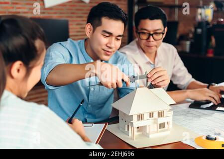 Engineering hands hold vernier caliper working and checking house model scale between meeting with businessman and businesswoman. Stock Photo