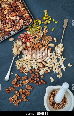 Various nuts with a tray of roasted nuts on a slate background Stock Photo