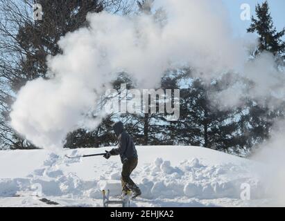 Mount Pleasant, Wisconsin, USA. 19th Feb, 2021. CHRIS HANSON uses steam to clear snow from the roof and gutters of a home in the Village of Mount Pleasant, Wisconsin Friday. The area received almost 17 inches of snow last Sunday and Monday. (Credit Image: © Mark HertzbergZUMA Wire) Stock Photo