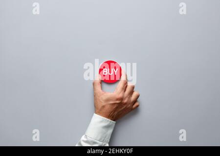 Businessman hand holding a red badge with the word buy. Buying decision in finance or real estate business. Stock Photo