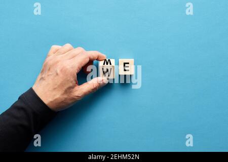 Male hand flipping wooden cube to change the word me to we. Teamwork, partnership, cooperation, team collaboration concept. Stock Photo