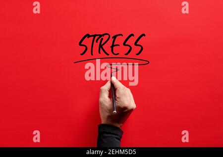 Male hand writing the word stress on red background. Overhead view. Stock Photo