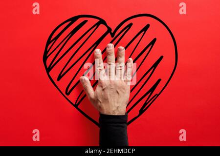 Male hand touching a hand drawn heart shape on red background. Stroke, heart attack or love and affection concept. Stock Photo
