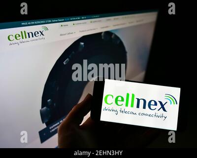 Person holding mobile phone with logo of Spanish telecommunications provider Cellnex Telecom S.A. on screen with website. Focus on cellphone display. Stock Photo