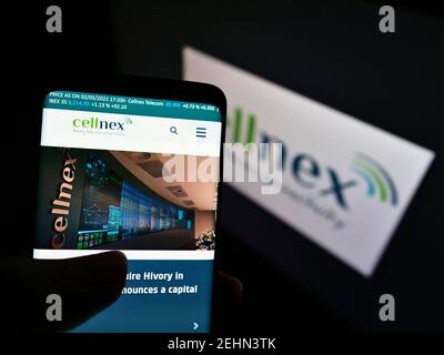 Person holding cellphone with website of Spanish telecommunications company Cellnex Telecom on screen with logo. Focus on center of phone display. Stock Photo