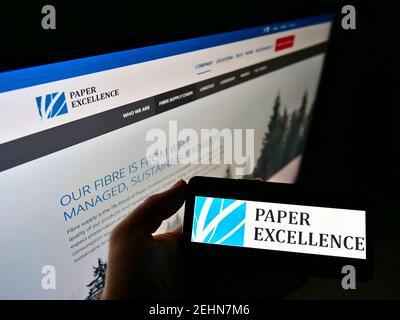 Person holding cellphone with logo of Canadian pulp and paper manufacturer Paper Excellence B.V. on screen with website. Focus on phone display. Stock Photo