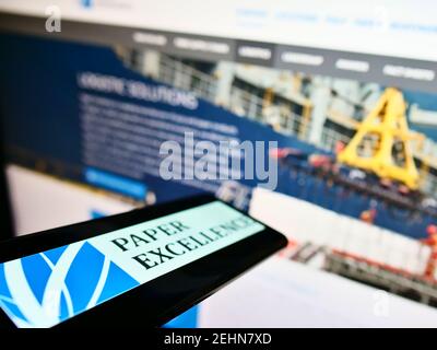 Mobile phone with logo of Canadian paper and pulp manufacturer Paper Excellence on screen in front of website. Focus on center-left of phone display. Stock Photo