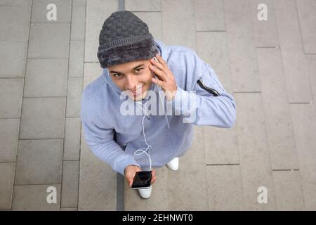Listening to music smiling young latin man runner sports training from above outdoor Stock Photo