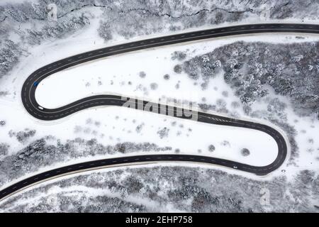 Aerial view of a winding serpentine road cutting through the lush green ...
