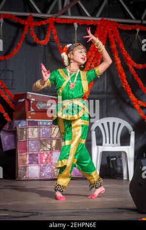 A female Indian dancer in an elegant green and gold costume performing during Diwali, the Hindu festival of light Stock Photo