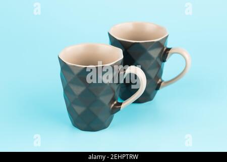 Two brown ceramic cups isolated on blue background. Stock Photo