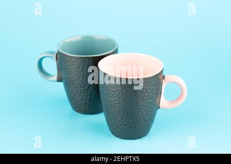 Two brown ceramic cups isolated on blue background. Stock Photo