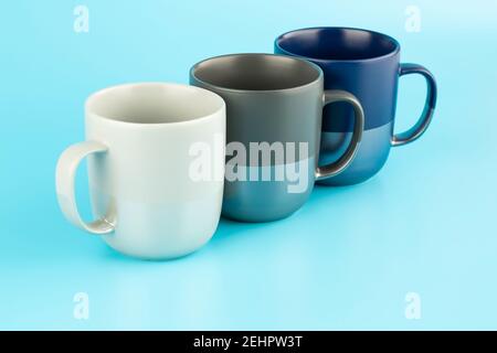 Three ceramic cups isolated on blue background. Stock Photo